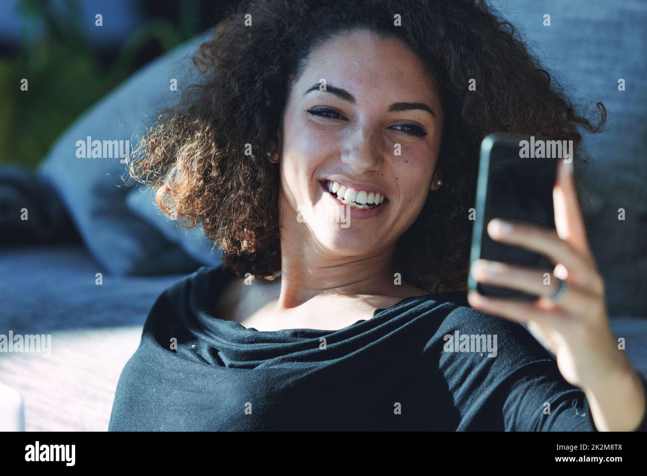 Amüsierte junge Frau, die über ihr Handy lacht Stockfoto