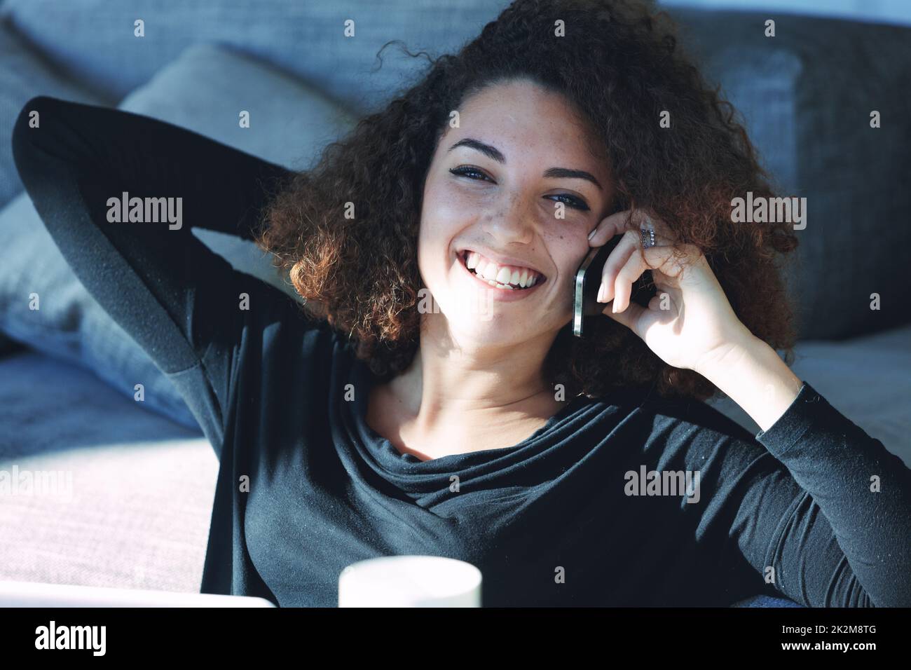 Fröhliche junge Frau, die auf ihrem Handy lacht und lächelt Stockfoto