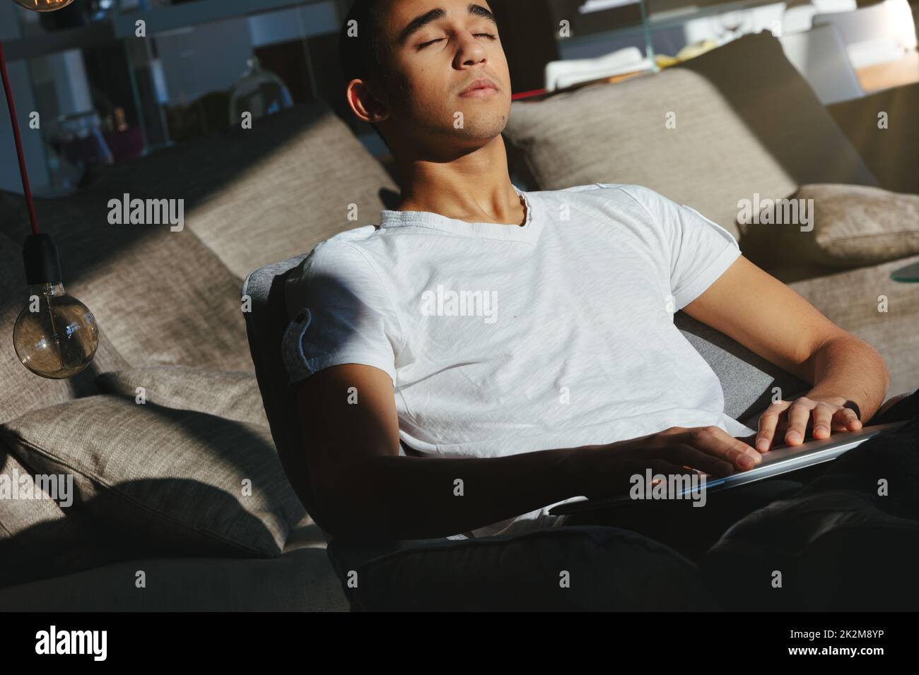 Ein Mann, der sich auf einer bequemen Couch entspannt und die warme Sonne genießt Stockfoto