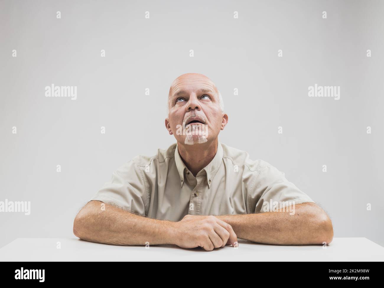 Ein gelangweilter Mann sitzt am Tisch Stockfoto