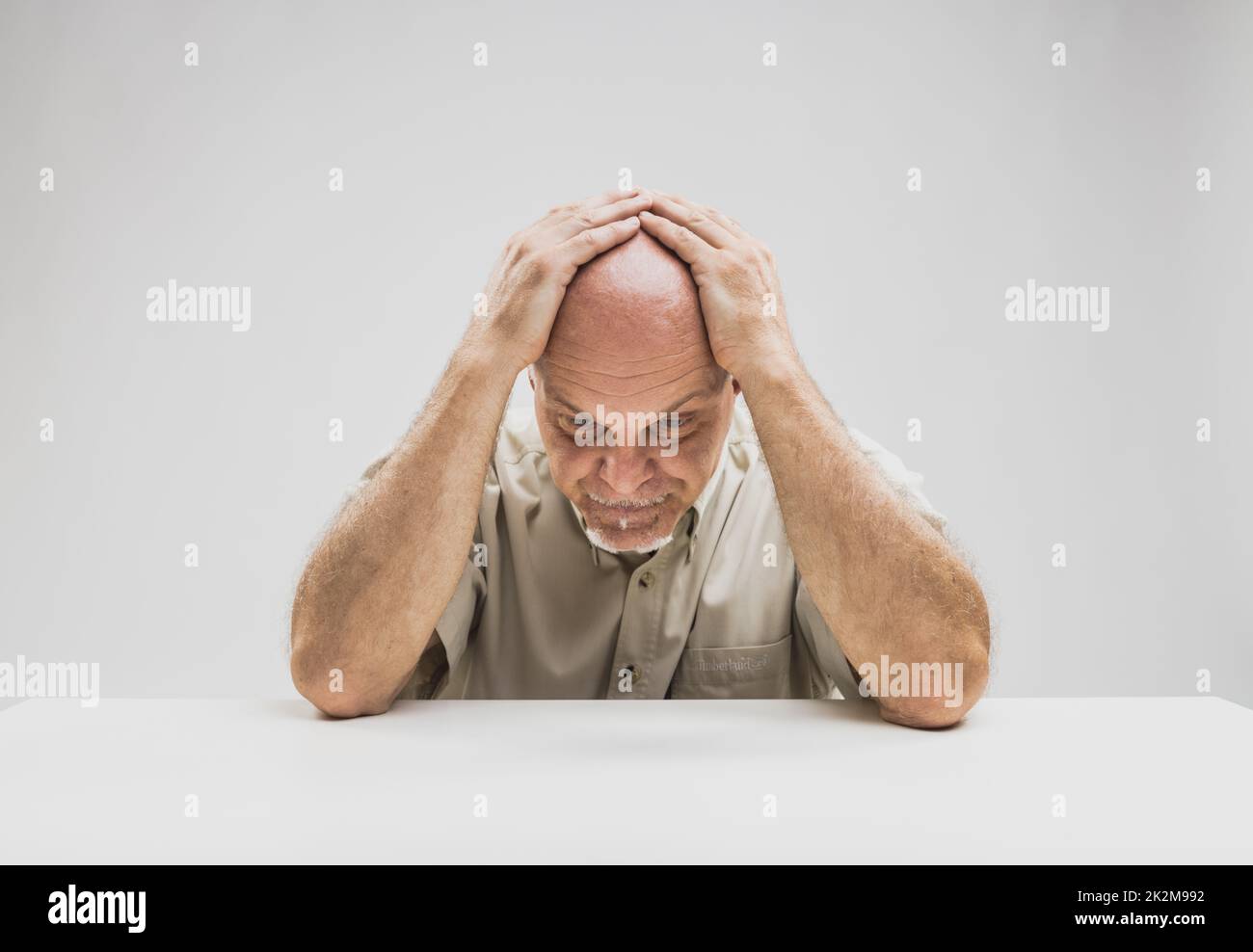 Deprimierter Mann, der am Tisch sitzt Stockfoto