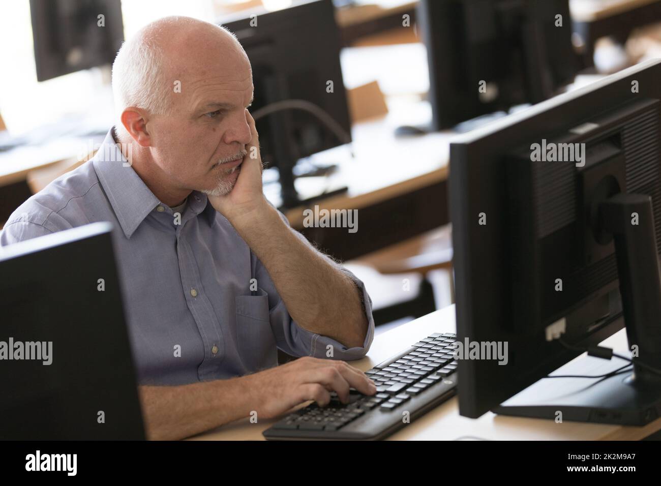 Aufmerksamer Geschäftsmann, der auf einen Desktop-Monitor starrt Stockfoto