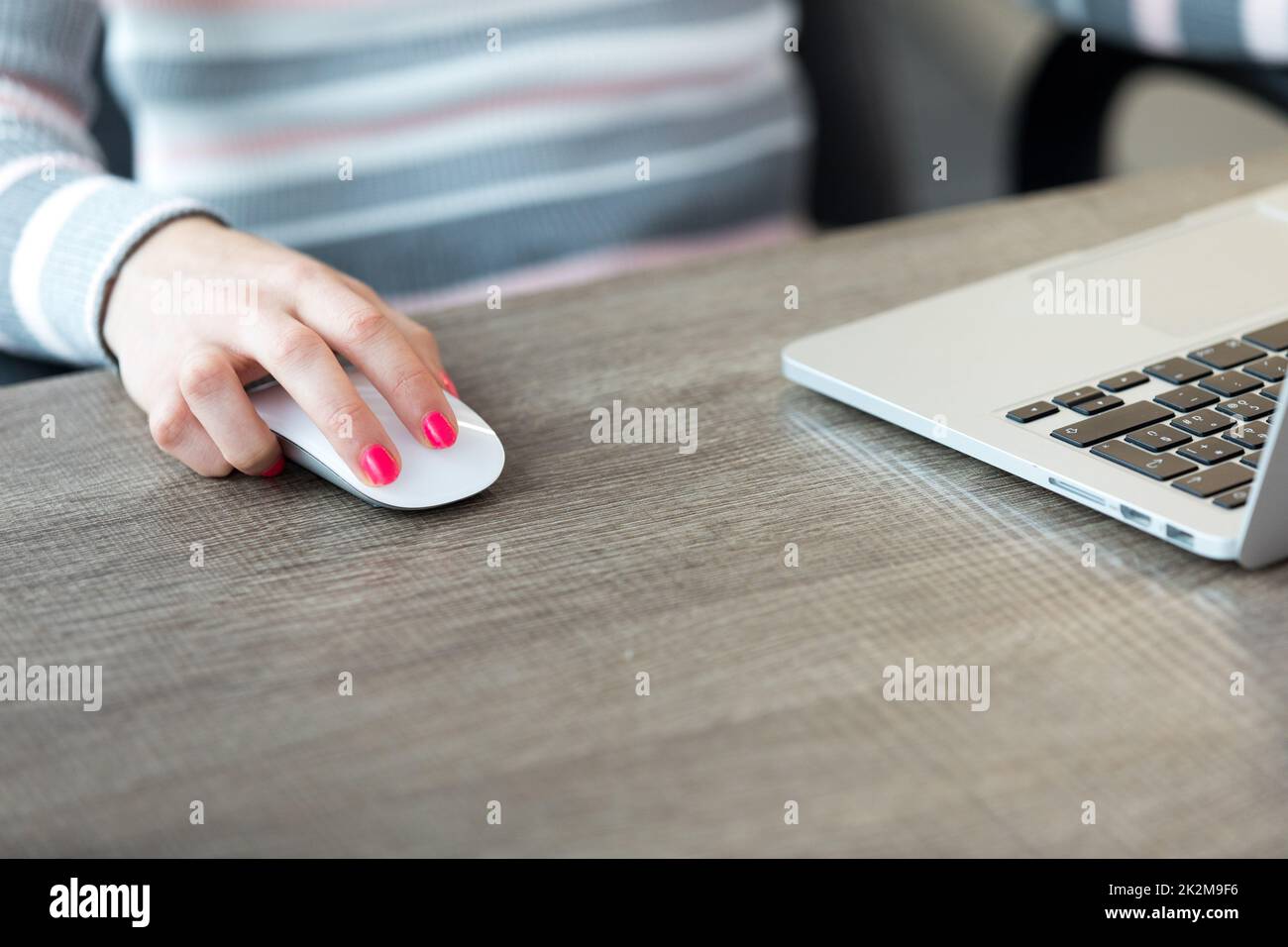 Weibliche Hand-Computermaus vor dem Laptop Stockfoto