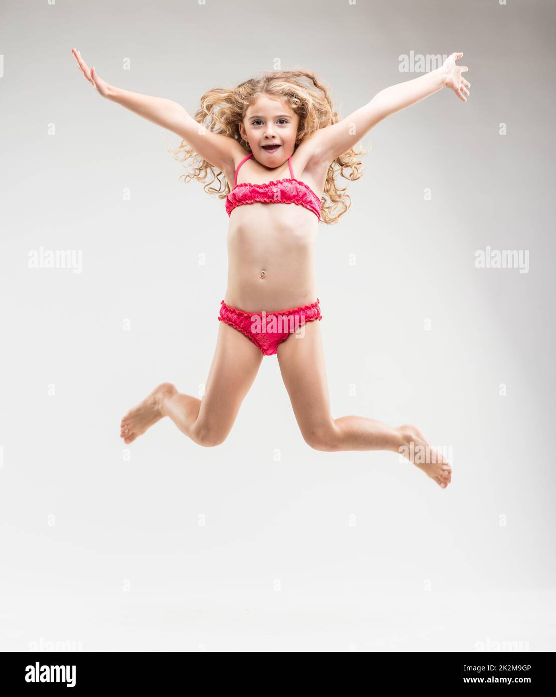 Agiles, überschwängliches kleines Mädchen, das in die Luft springt Stockfoto