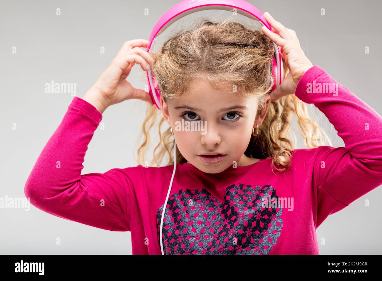 L Girl hört Musik auf pinkfarbenen Kopfhörern Stockfoto