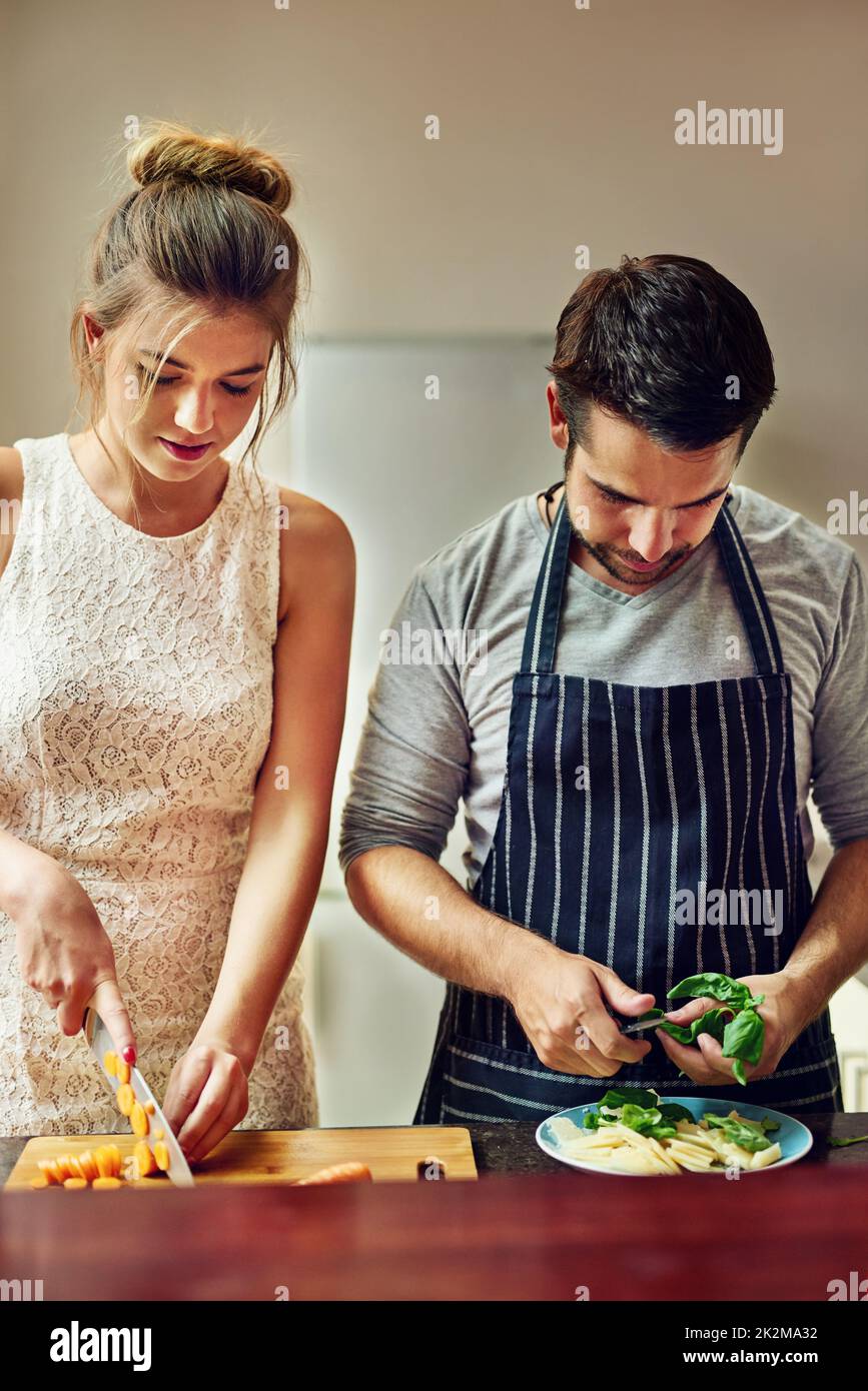 Essen schmeckt besser, wenn wir zusammen kochen. Aufnahme eines jungen Paares, das zu Hause zusammen Essen zubereitete. Stockfoto