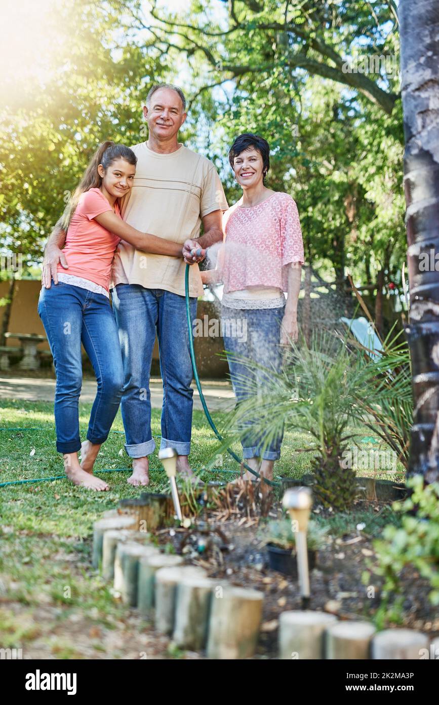Eine große glückliche Familie. Porträt einer Familie, die einen Garten mit einem Schlauch bewässert. Stockfoto