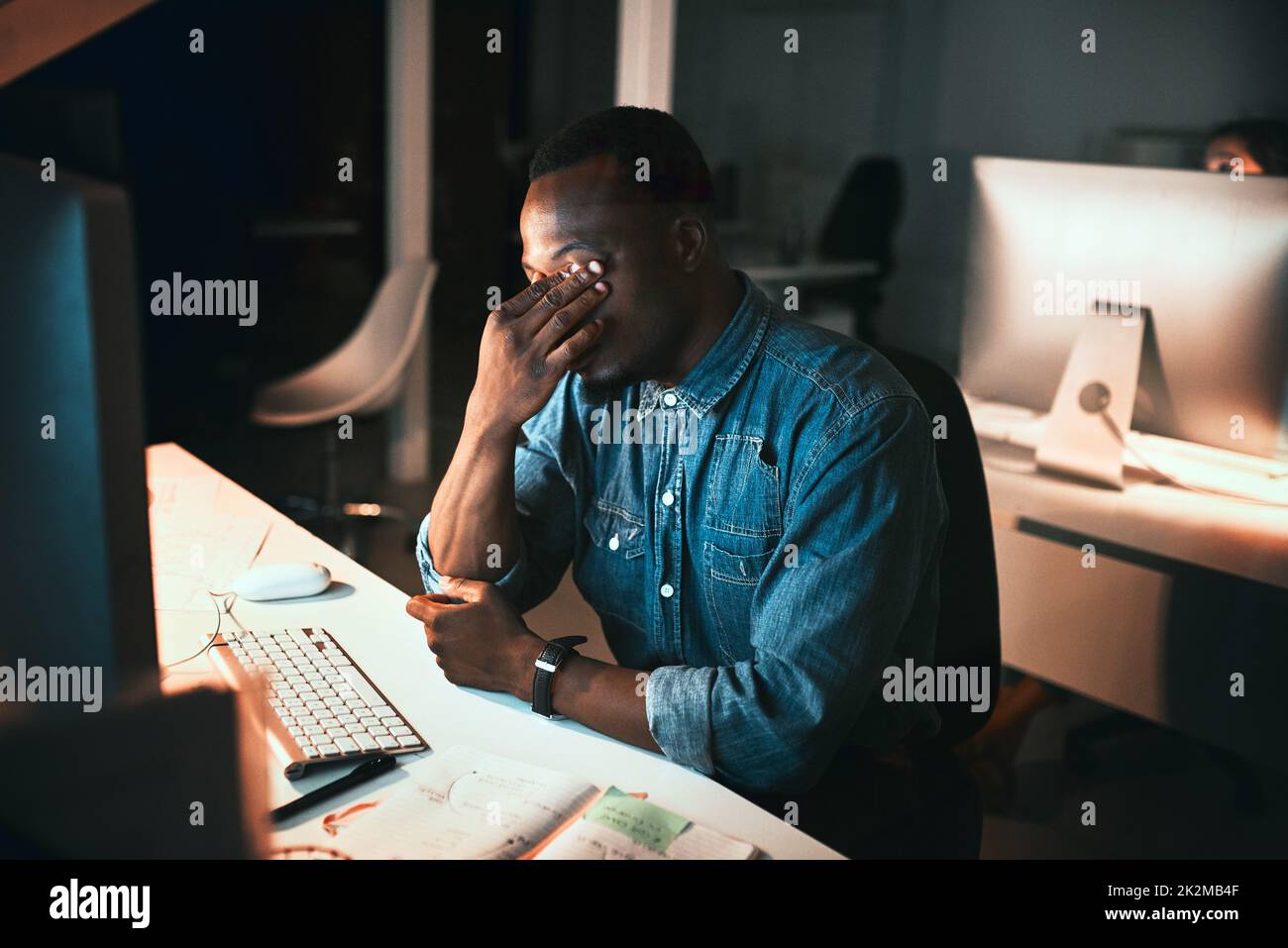 Sich durch die Frist unter Druck gesetzt zu fühlen. High-Angle-Aufnahme eines jungen männlichen Designers, der während der Arbeit am Computer im Büro gestresst aussieht. Stockfoto