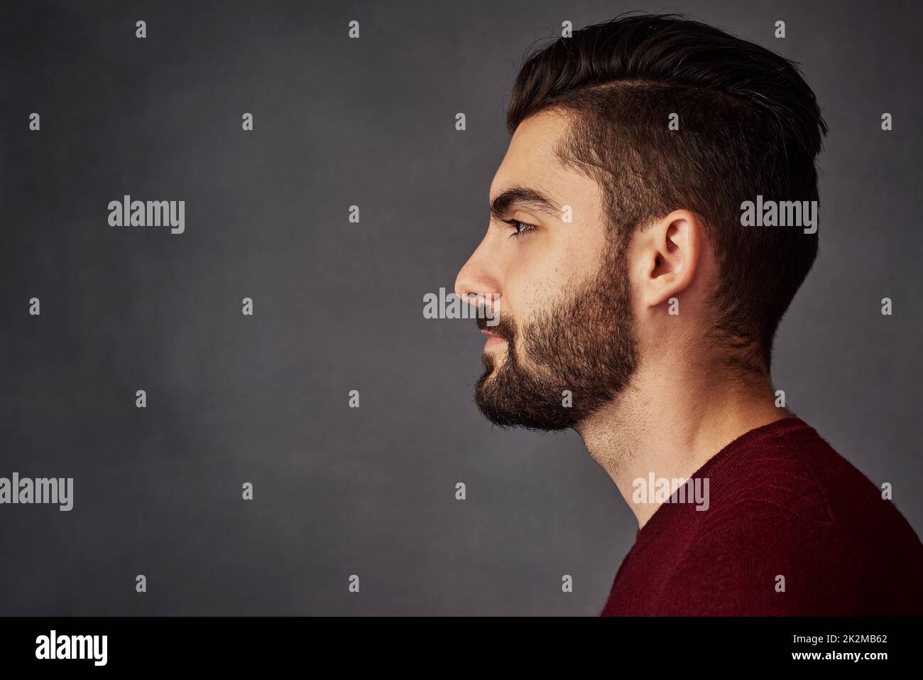 Attraktiv aus jedem Blickwinkel. Studioaufnahme eines hübschen jungen Mannes, der vor dunklem Hintergrund posiert. Stockfoto