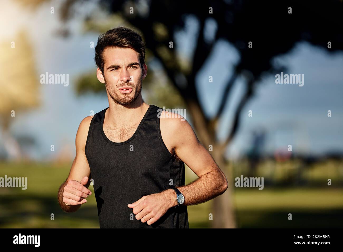 Machen Sie einfach weiter. Aufnahme eines jungen Mannes, der in einem Park joggt. Stockfoto