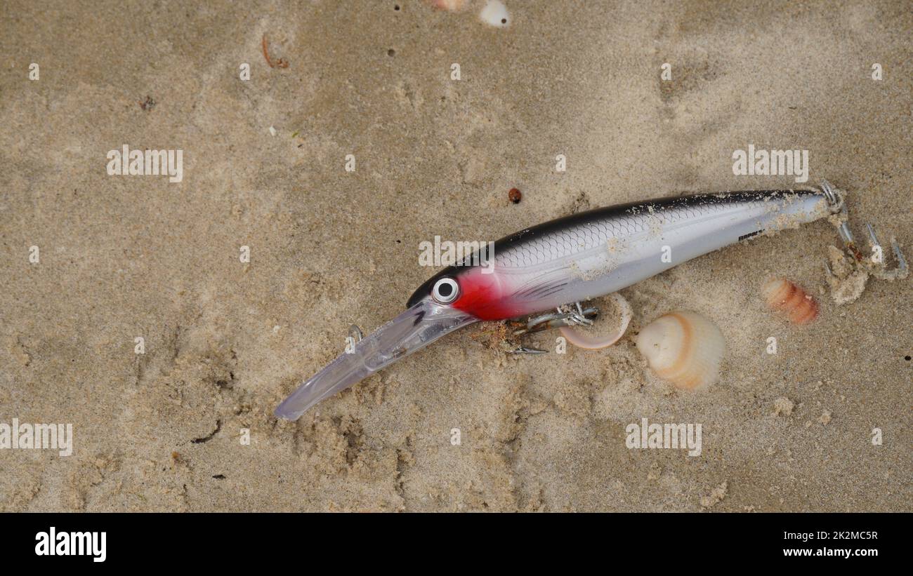 Eine ausrangierte Angel liegt am Sandstrand. Stockfoto