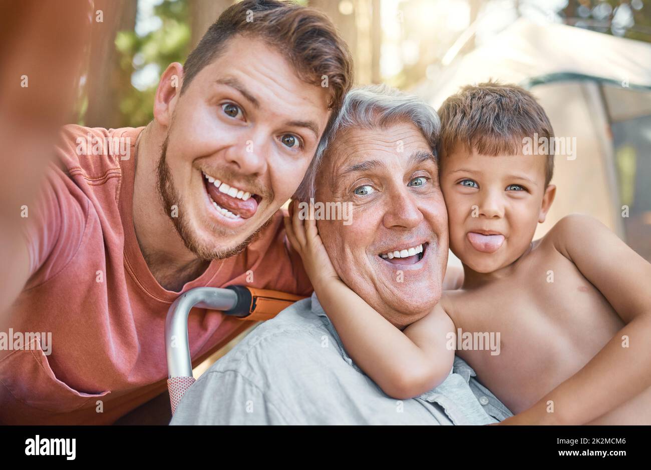 Viel Spaß für die ganze Familie. Beschnittenes Porträt eines hübschen jungen Mannes, der mit seinem Vater und seinem Sohn Selfies macht, während er im Wald kampiert. Stockfoto