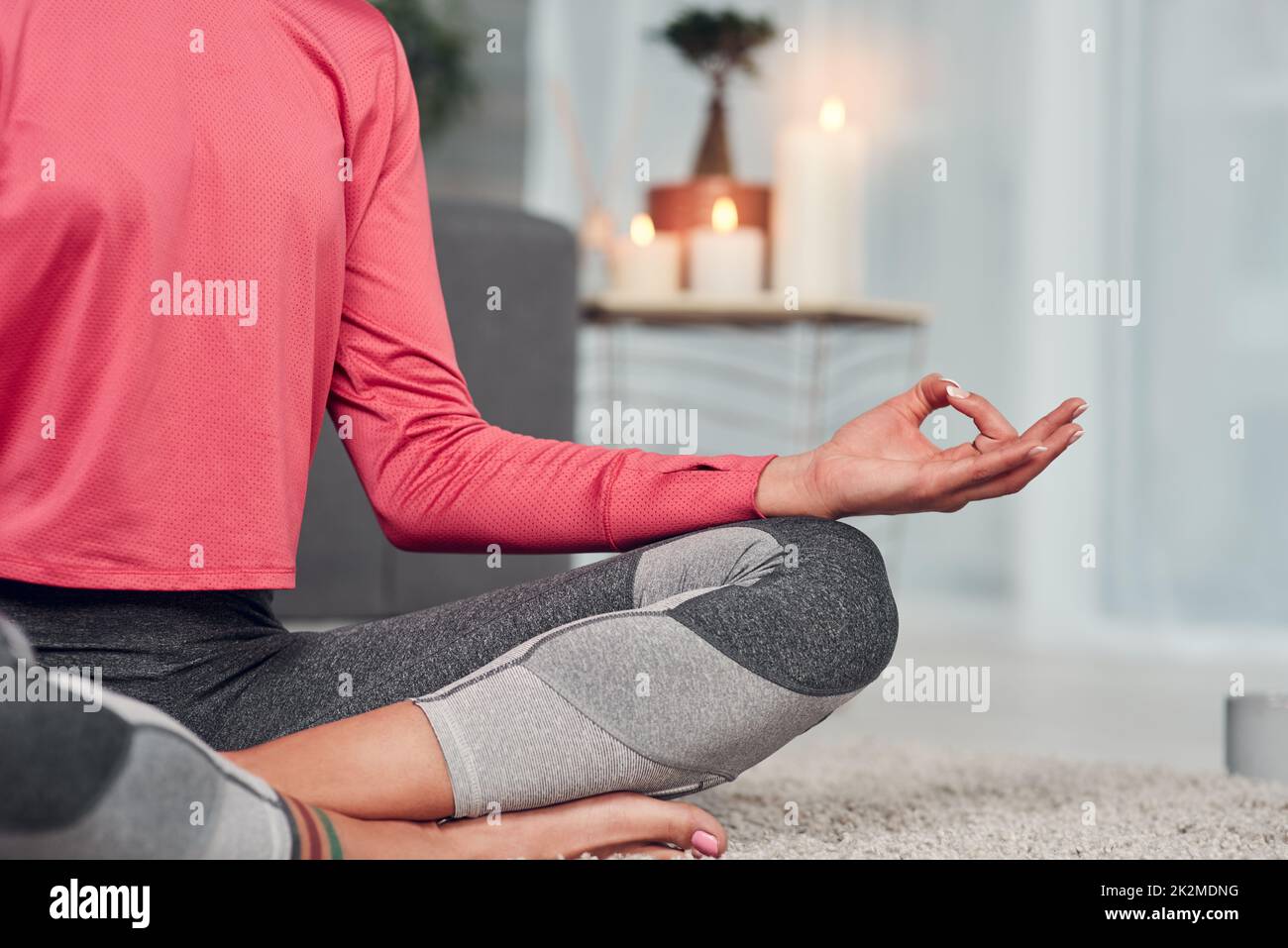 Meine Chakren ausbalancieren. Zugeschnittene Aufnahme einer unkenntlich gekreuzten Frau, die zu Hause in ihrem Wohnzimmer meditiert. Stockfoto