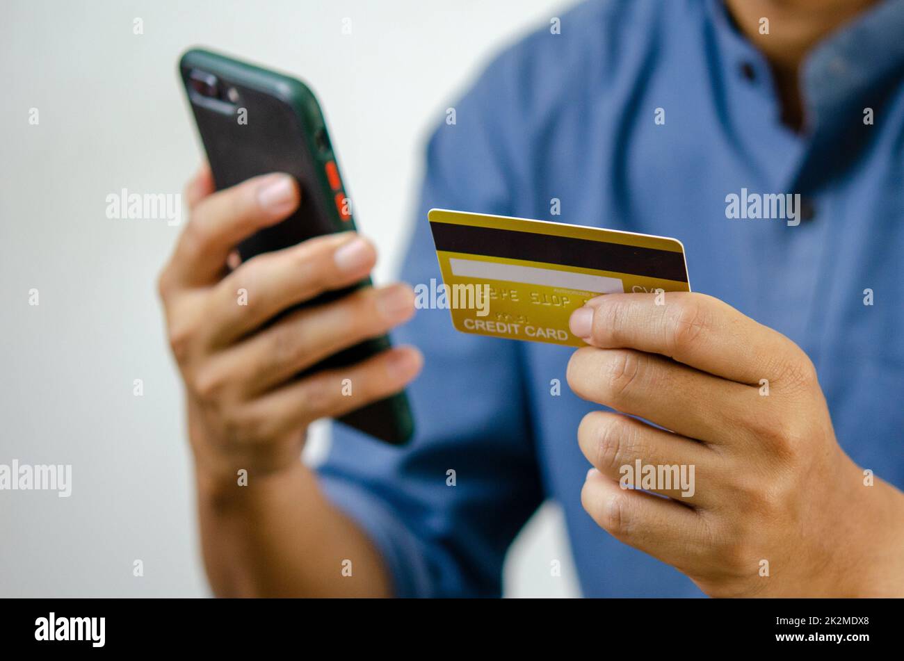 Mann Hand hält Kreditkarte und Handy Online-Shopping E-Commerce und Internet-Banking. Stockfoto