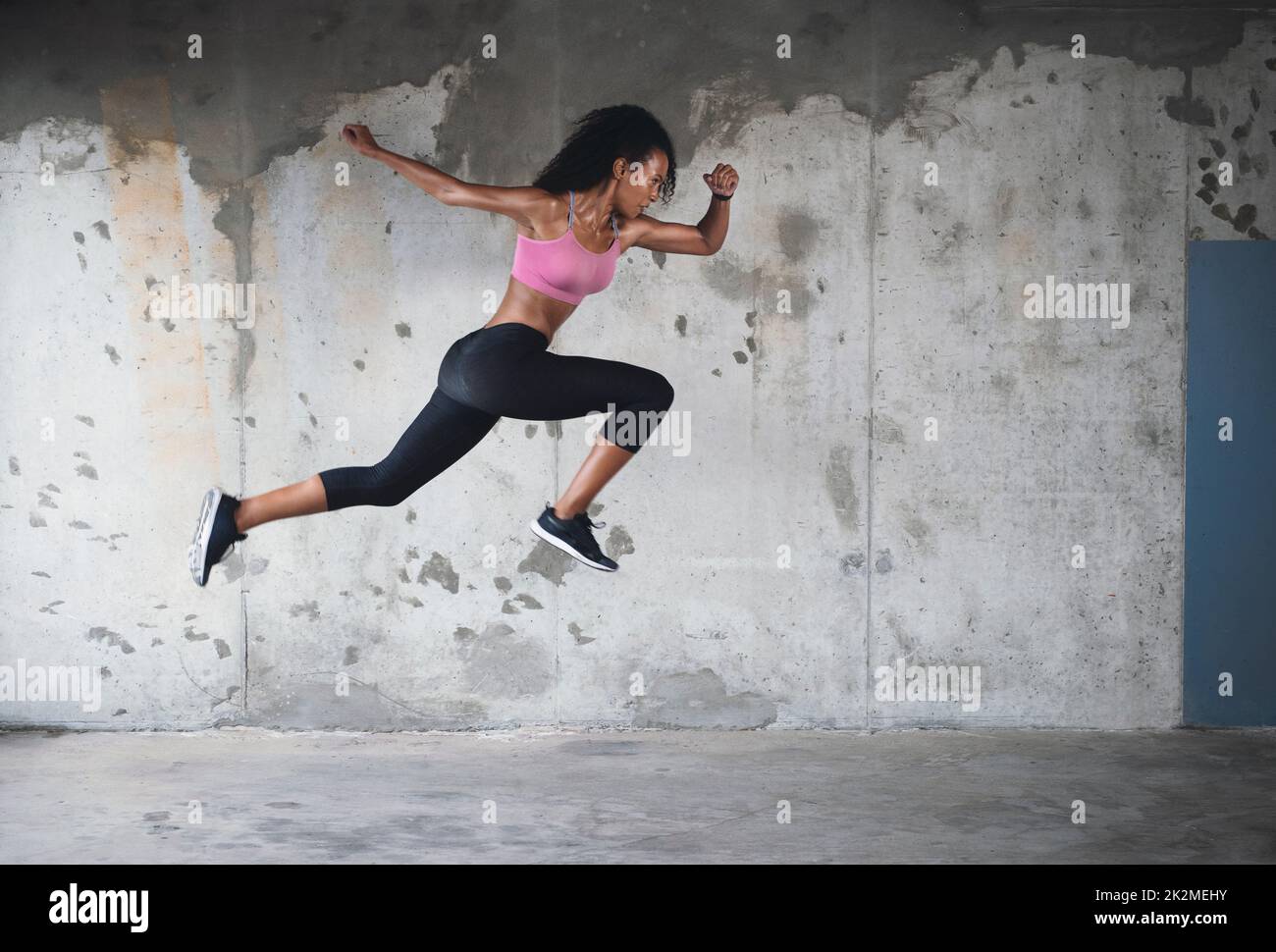 Zurück in Aktion. Ganzkörperaufnahme einer athletischen jungen Sportlerin, die im Freien in der Luft gegen eine Wand springt. Stockfoto