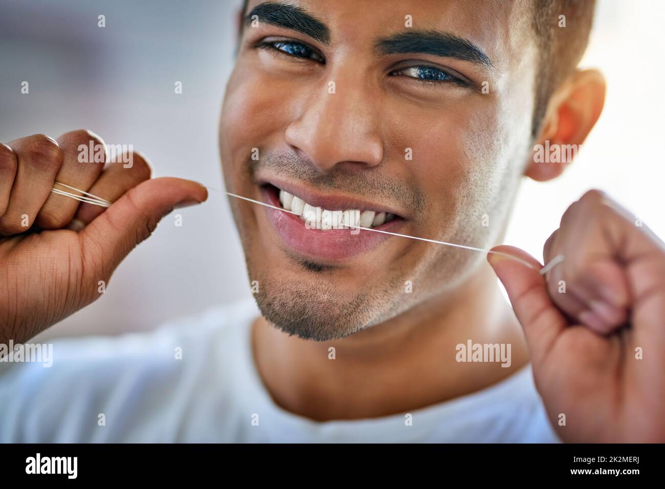 Mein Lächeln verlangt, dass ich das tue. Porträt eines glücklichen jungen Mannes, der zu Hause seine Zähne mit Zahnseide verputzt. Stockfoto