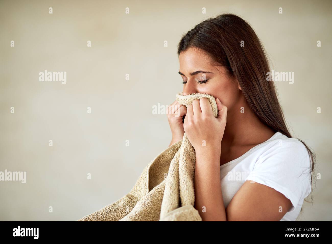 Flauschig und frisch. Aufnahme einer jungen Frau, die den Geruch frisch gewaschenen Handtüchern genießt. Stockfoto