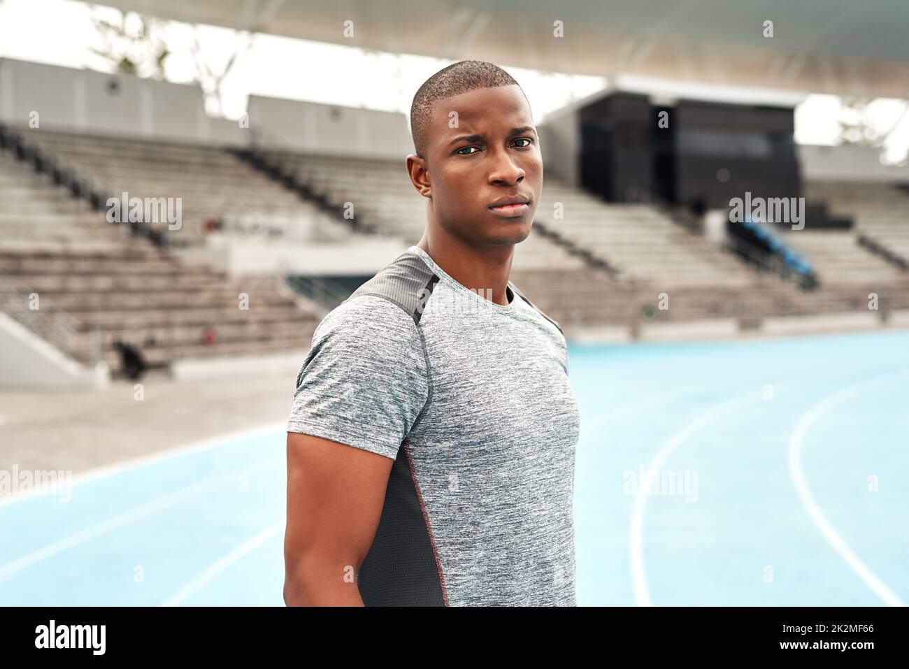 Wage es, mich herauszufordern. Beschnittenes Porträt eines hübschen jungen Sportlers, der allein steht, bevor er auf einem Sportfeld läuft. Stockfoto
