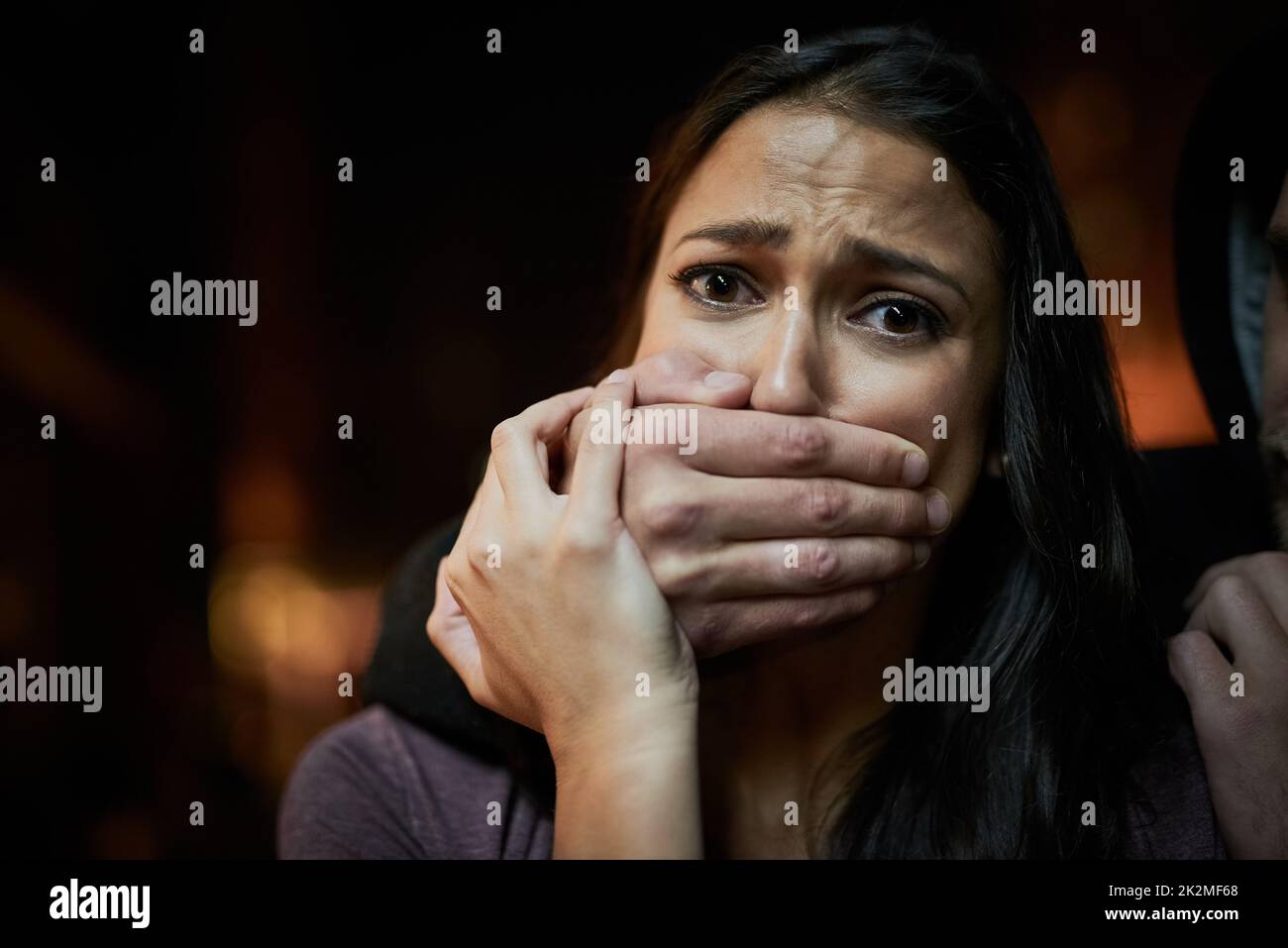 Wehrlos und in Gefahr. Porträt einer verängstigten jungen Frau mit ihren Angreifern über ihren Mund. Stockfoto