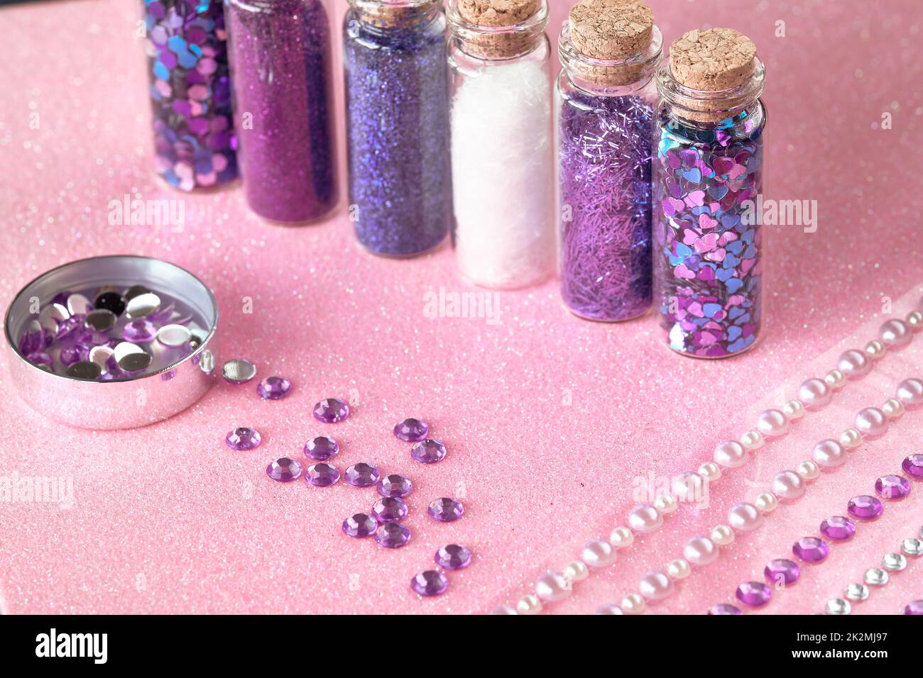Alle Arten von Glitter-Produkten auf rosa glitzerndem Hintergrund. Nahaufnahme von Fläschchen, Flaschen mit verschiedenen Glitzer-Make-up in Neonpink, Blau und Türkis. Stockfoto