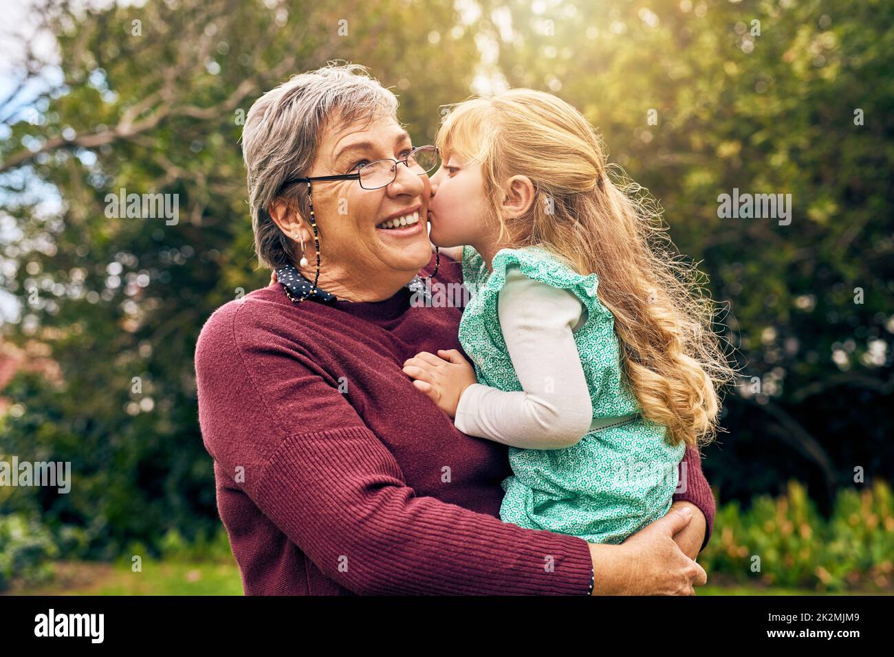 Du wirst immer Grannys kleines Mädchen sein. Schuss einer Enkelin, die draußen ihre Großmutter auf die Wange küsst. Stockfoto