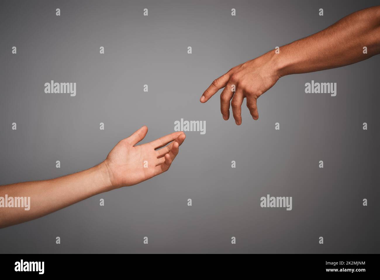 Treten Sie mit Ihrer klassischen Seite in Kontakt. Studioaufnahme von nicht identifizierbaren Händen, die sich vor grauem Hintergrund gegenseitig erreichen. Stockfoto