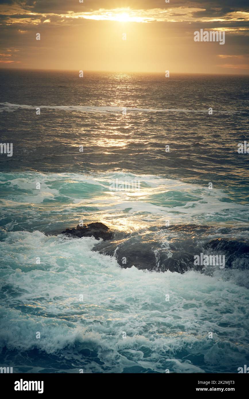 Folgen Sie dem Meer und machen einige Wellen. Aufnahme von Meereswellen, die gegen Felsbrocken an der Küste stürmen. Stockfoto