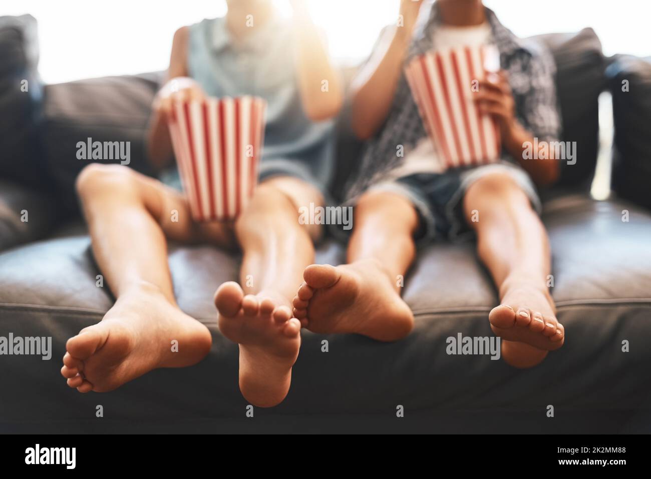 Seine Filmzeit. Eine kurze Aufnahme eines Bruders und einer Schwester, die zu Hause Popcorn essen und Filme auf dem Sofa ansehen. Stockfoto