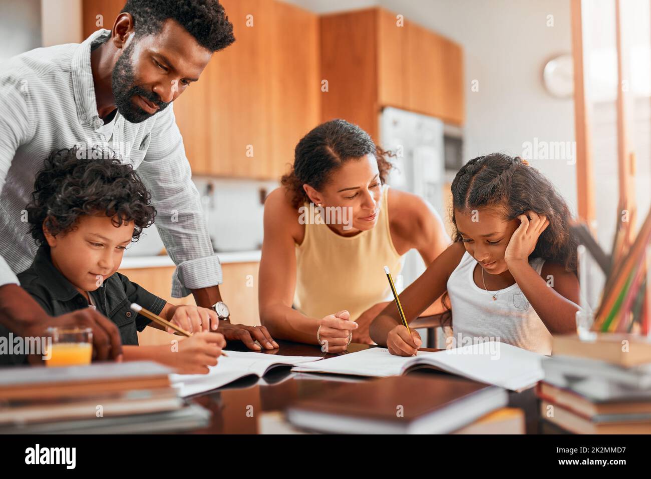 Helfen Sie Ihrem Kind, seine Zeit zu verwalten. Aufnahme von Eltern, die ihren beiden Kindern bei ihren Hausaufgaben helfen. Stockfoto