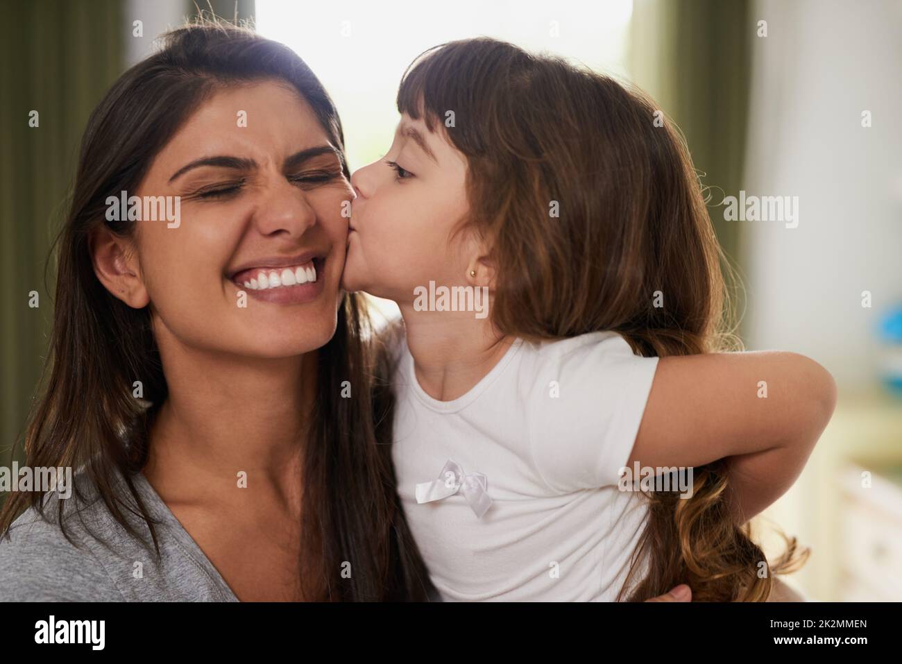 Und ein großes Kissy für Mama. Aufnahme eines kleinen Mädchens, das ihrer Mutter zu Hause einen Kuss auf die Wange gab. Stockfoto