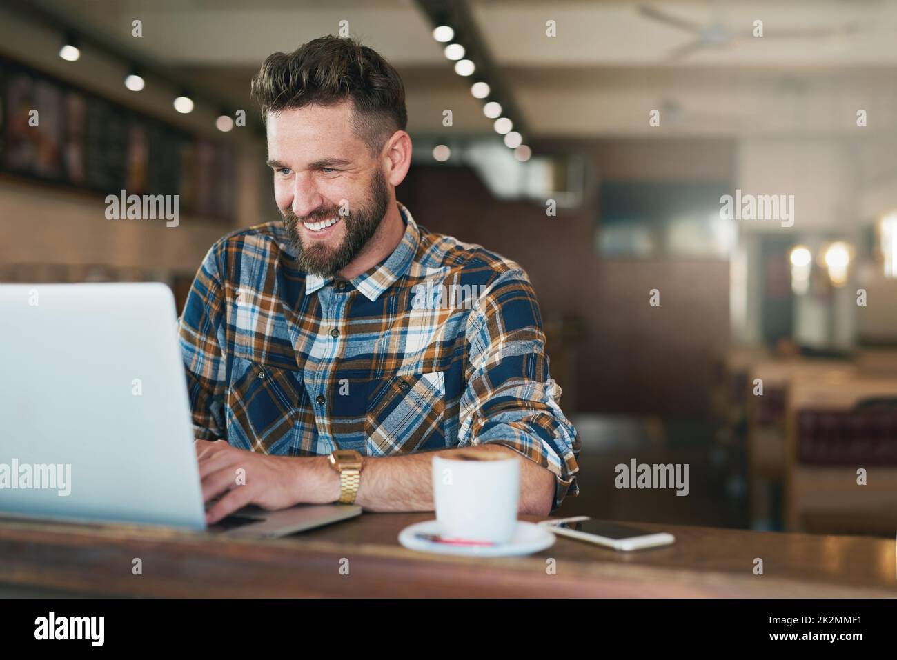 Kaffee- und Katzenvideos - eine klassische Kombination. Aufnahme eines jungen Mannes, der seinen Laptop benutzte, während er in einem Café am Fenster saß. Stockfoto