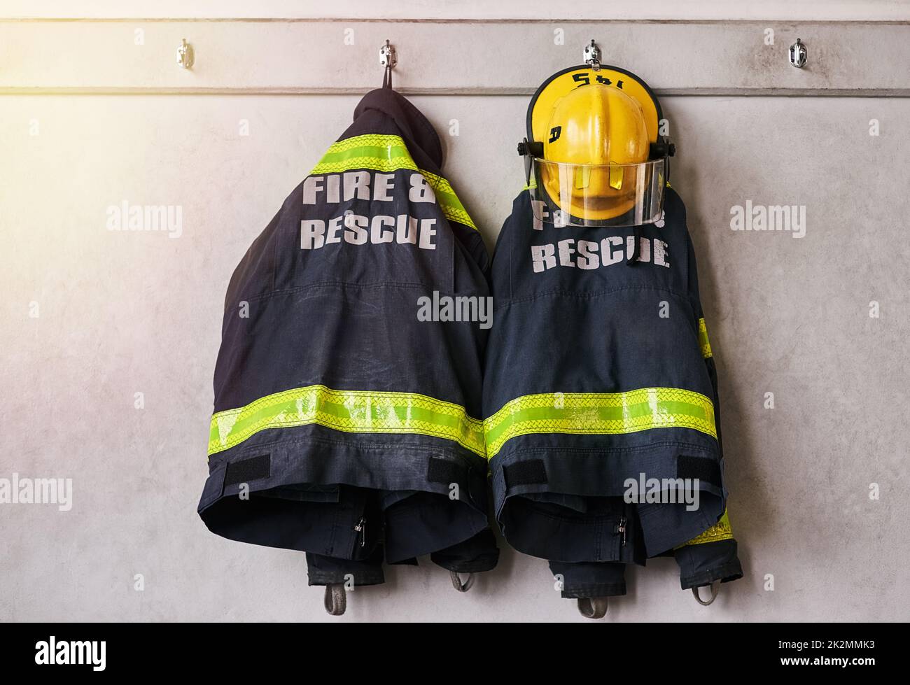 Feuer und Rettung. Kurzer Schuss von Feuerwehrkleidung, die an einer Wand hängt. Stockfoto