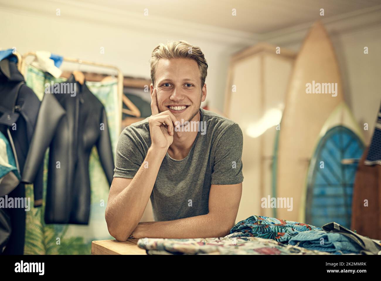 Ich habe alle Surfausrüstung, die man braucht. Porträt eines jungen Ladenbesitzers, der in seinem Surf-Shop posiert. Stockfoto