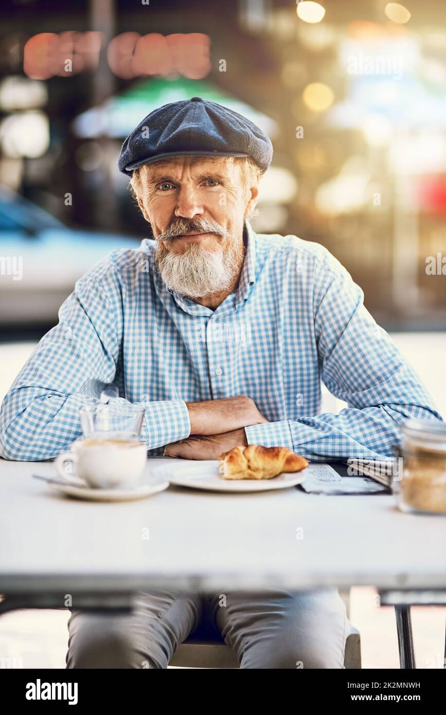 Der Ruhestand sieht gut aus für Sie. Porträt eines glücklichen älteren Mannes, der eine Tasse Kaffee in einem Straßencafé genießt. Stockfoto
