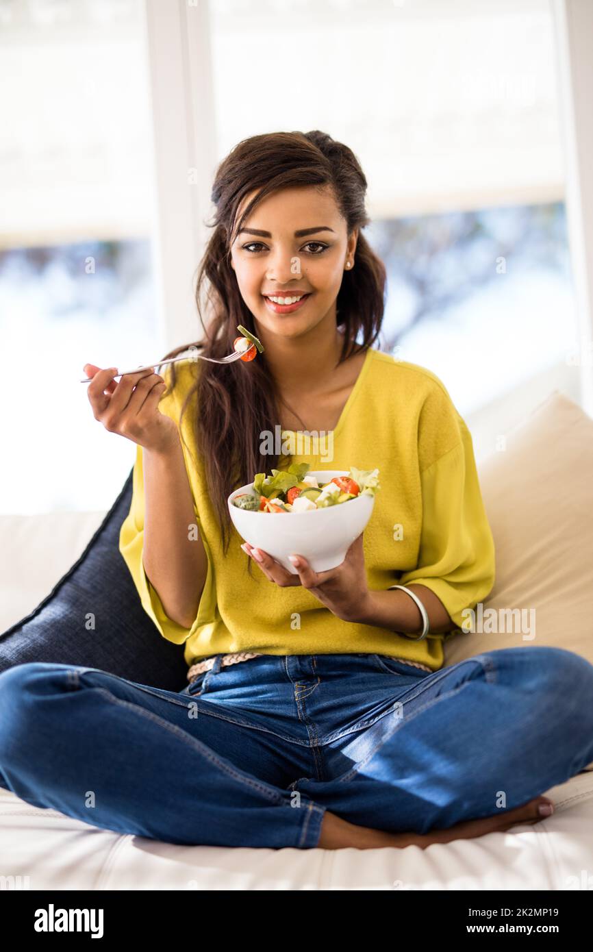 Gesund und lecker. Porträt einer jungen Frau, die zu Hause einen Salat isst. Stockfoto