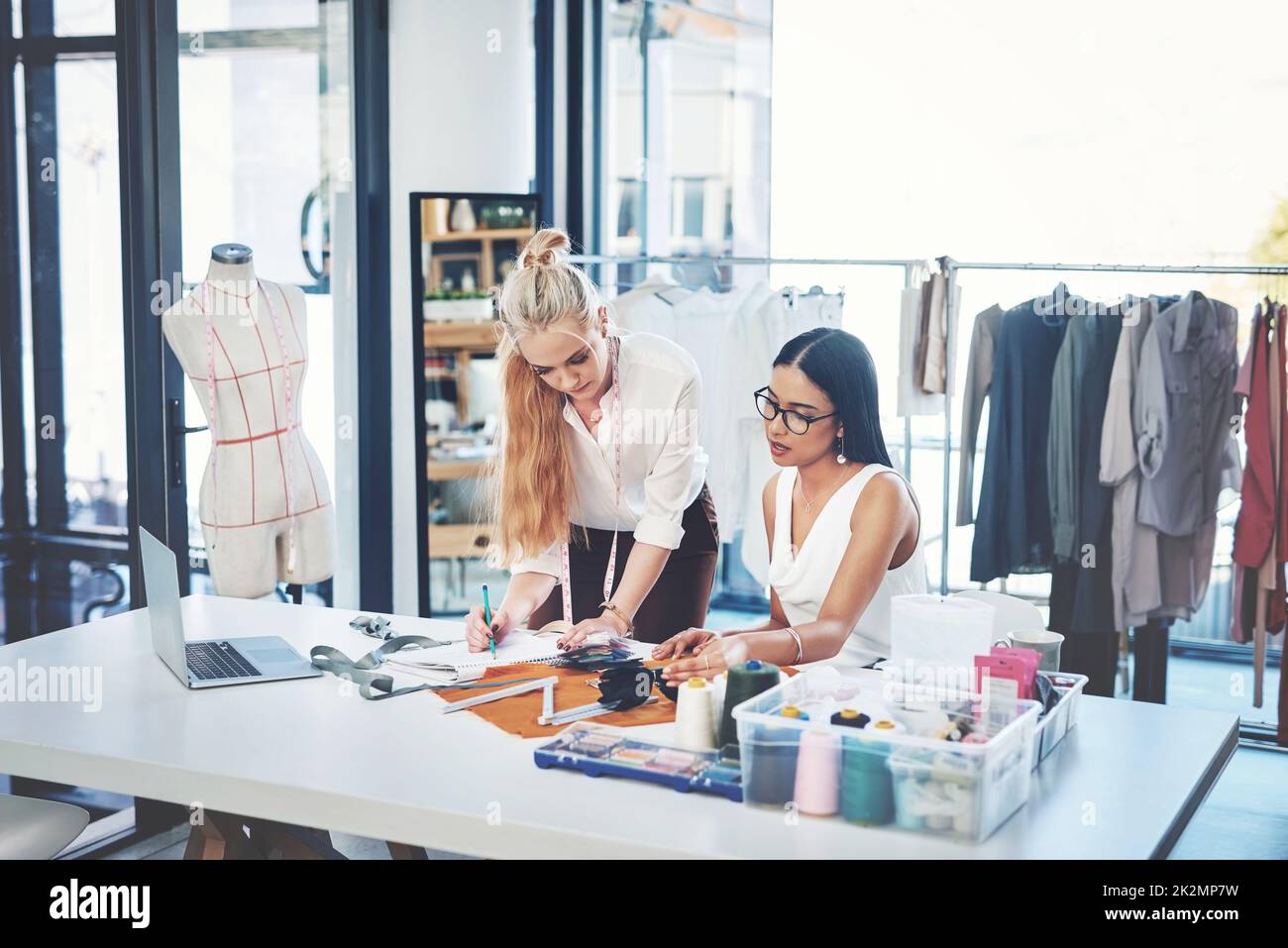 Unsere Kunden lieben es, wenn wir an Designs zusammenarbeiten. Aufnahme von zwei jungen Modedesignern, die in einem Workshop zusammenarbeiten. Stockfoto