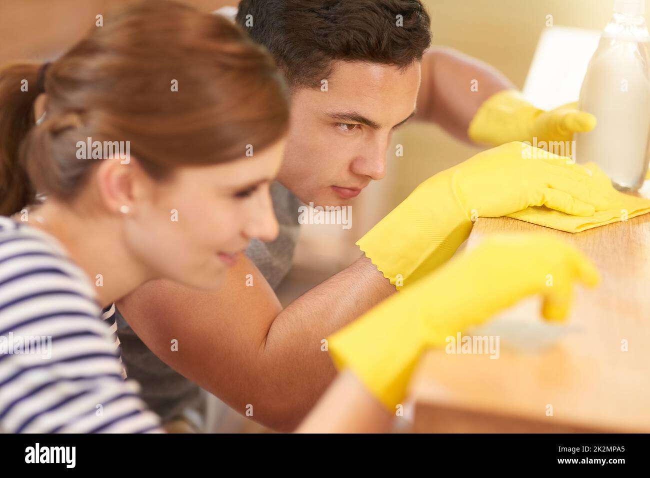 Sie perfektionierten die Reinigung zu einer Kunst. Aufnahme eines glücklichen jungen Paares, das gemeinsam ihre Küche putzte. Stockfoto