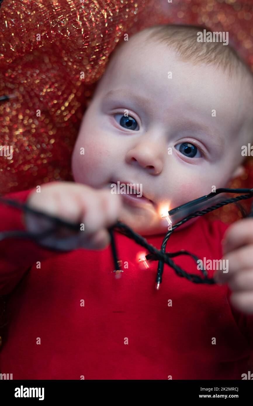 Ein niedliches Weihnachtsbaby, das mit Partylichtern spielt Stockfoto