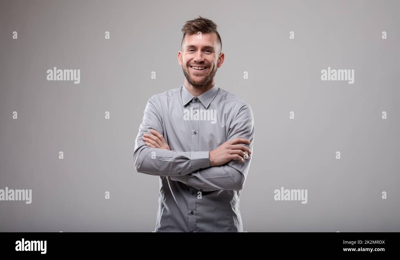 Glücklicher selbstbewusster Mann mit gefalteten Armen Stockfoto