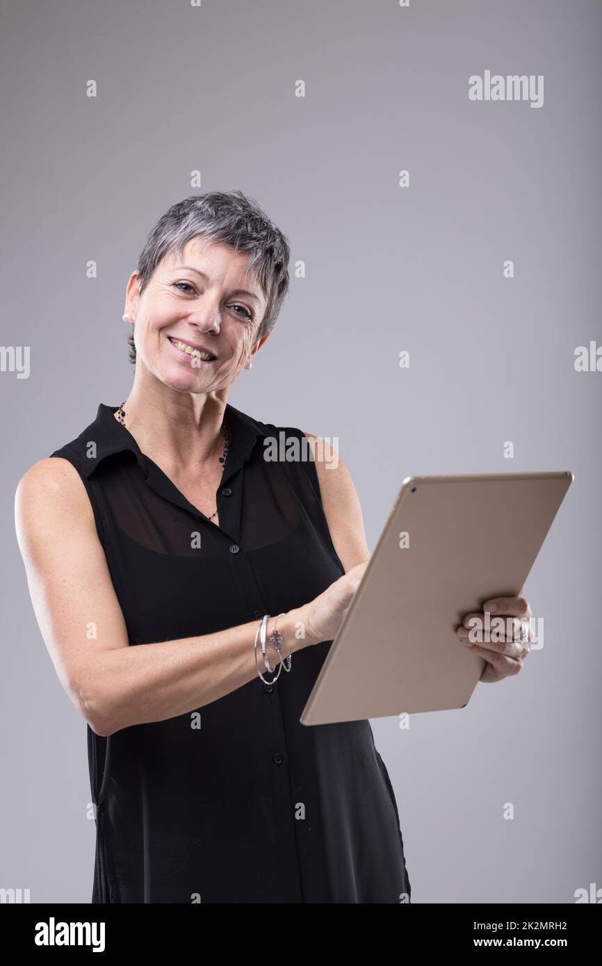 Attraktive Geschäftsfrau mittleren Alters, die ein Tablet benutzt Stockfoto