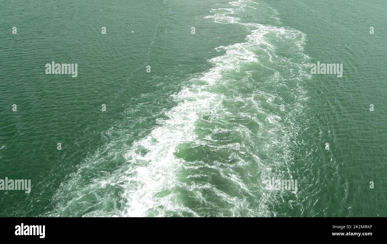 Eine schäumende, sprudelnde Spur auf der blauen Wasseroberfläche durch die Bewegung eines großen Schiffes auf See Stockfoto