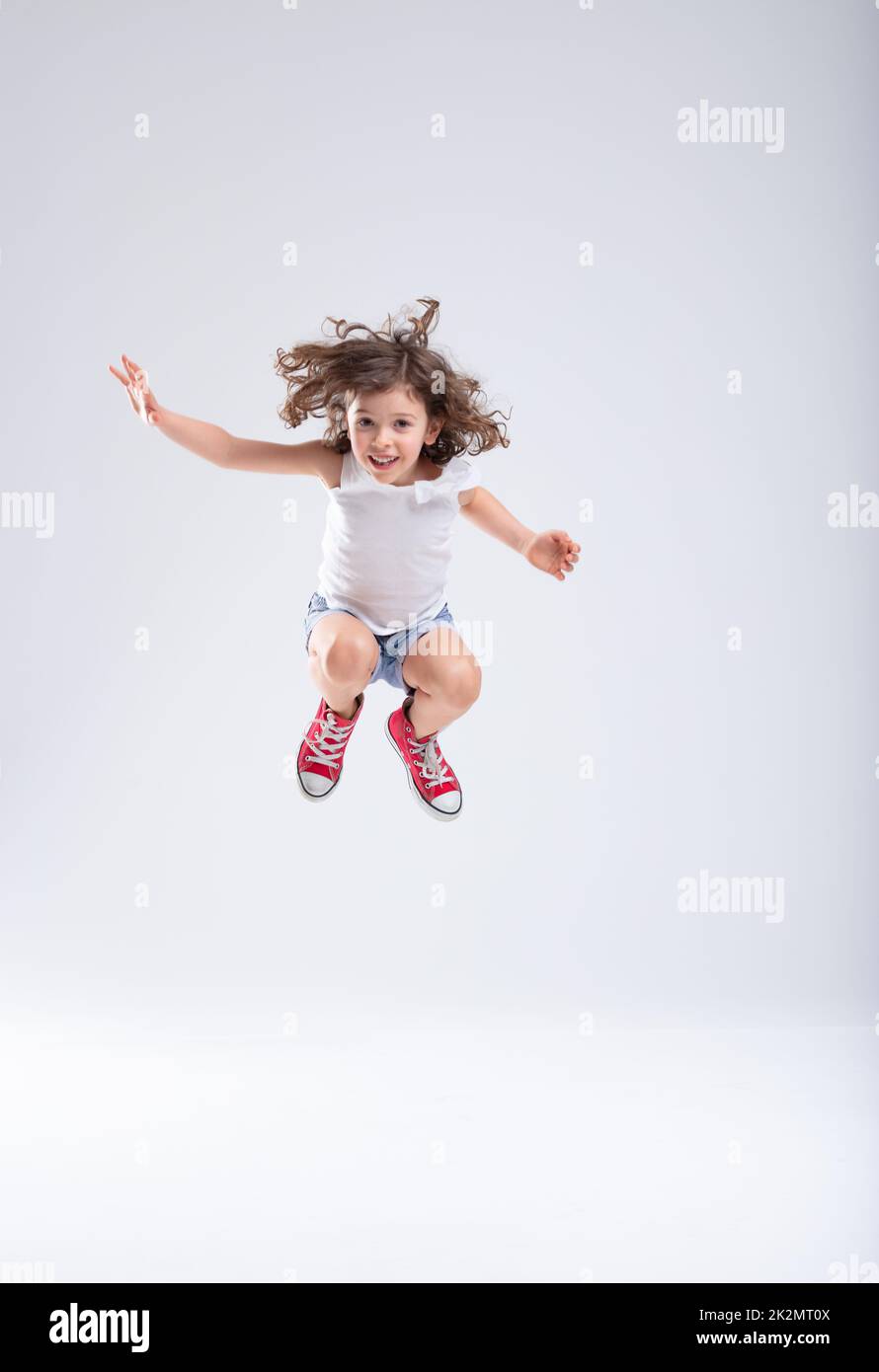 Ein energiegeladenes kleines Mädchen, das hoch in die Luft springt Stockfoto
