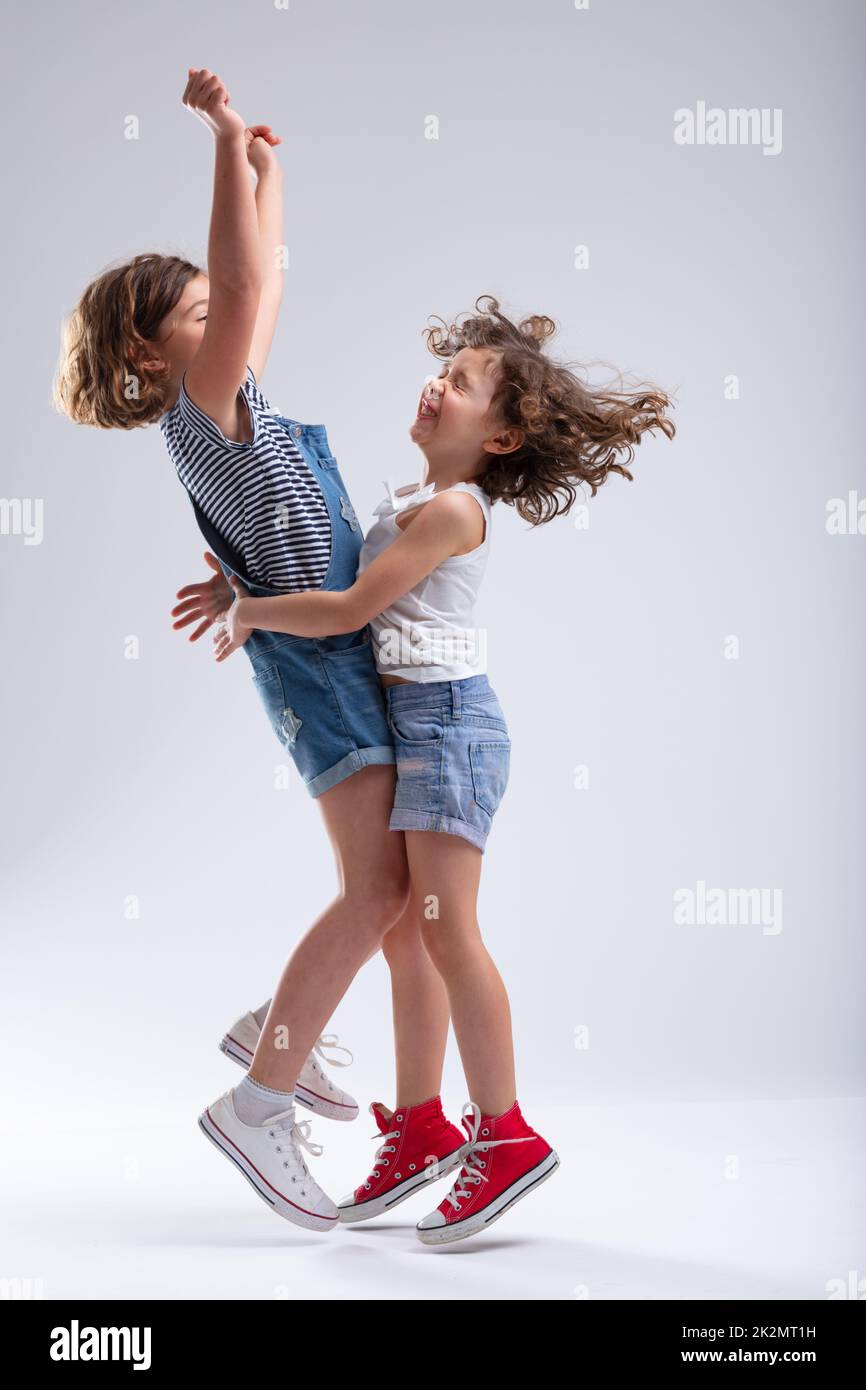 Zwei glückliche kleine Mädchen, die sich umarmen und springen Stockfoto