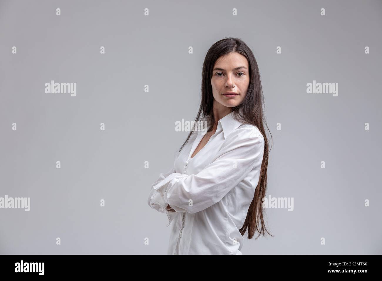 Langhaarige braune Frau mit verschränkten Armen Stockfoto