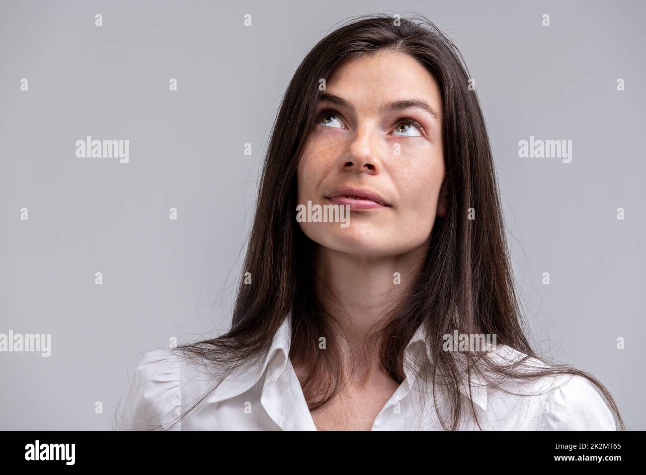 Attraktive Frau, die tief in Gedanken nach oben schaut Stockfoto