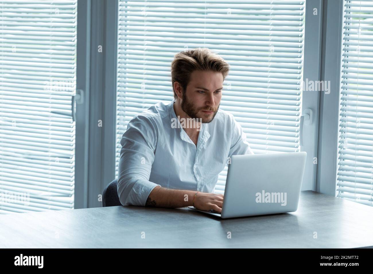 Seriöser junger Geschäftsmann, der an einem Notebook arbeitet Stockfoto
