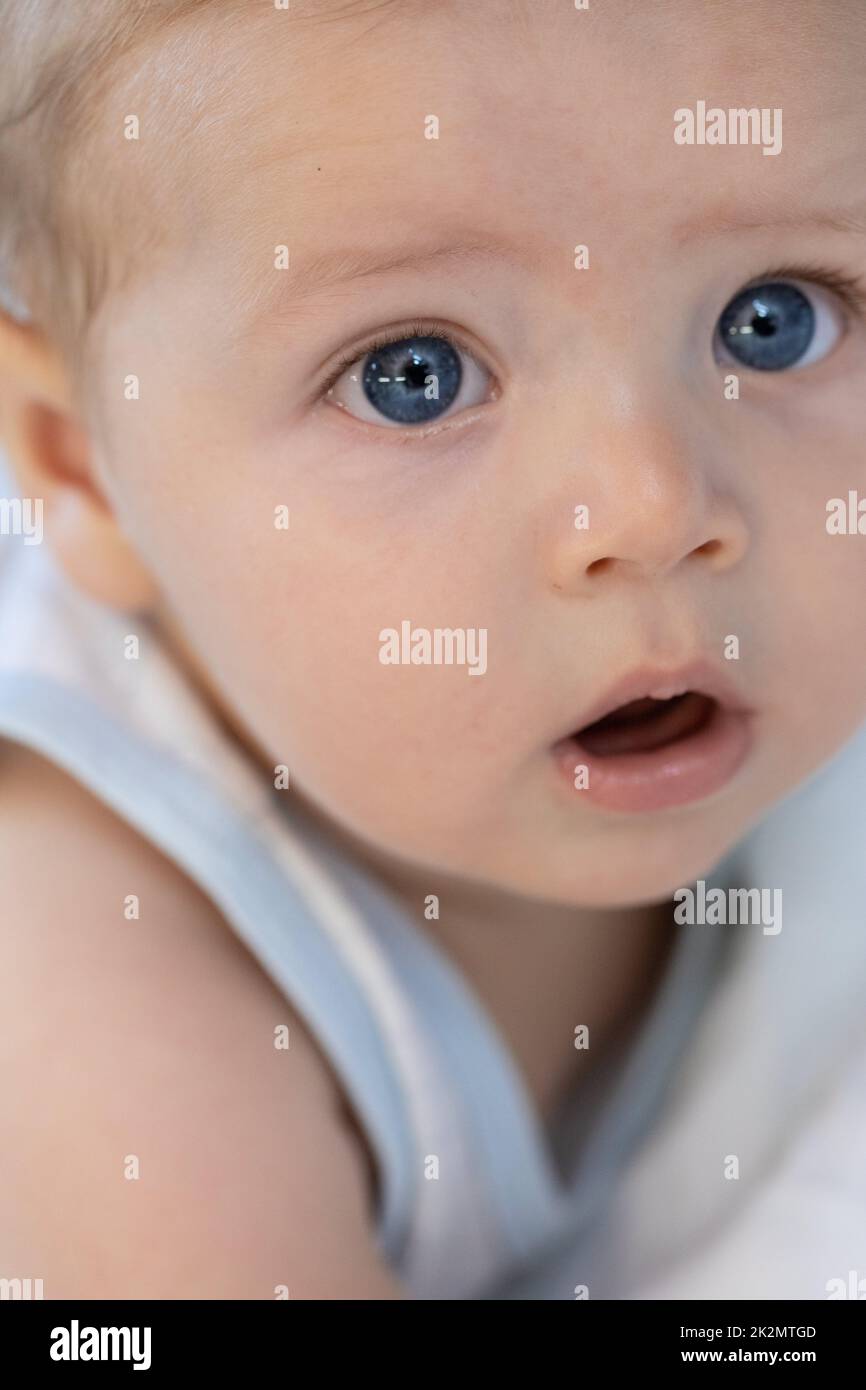 Kleines Baby mit großen vertrauensvollen blauen Augen Stockfoto