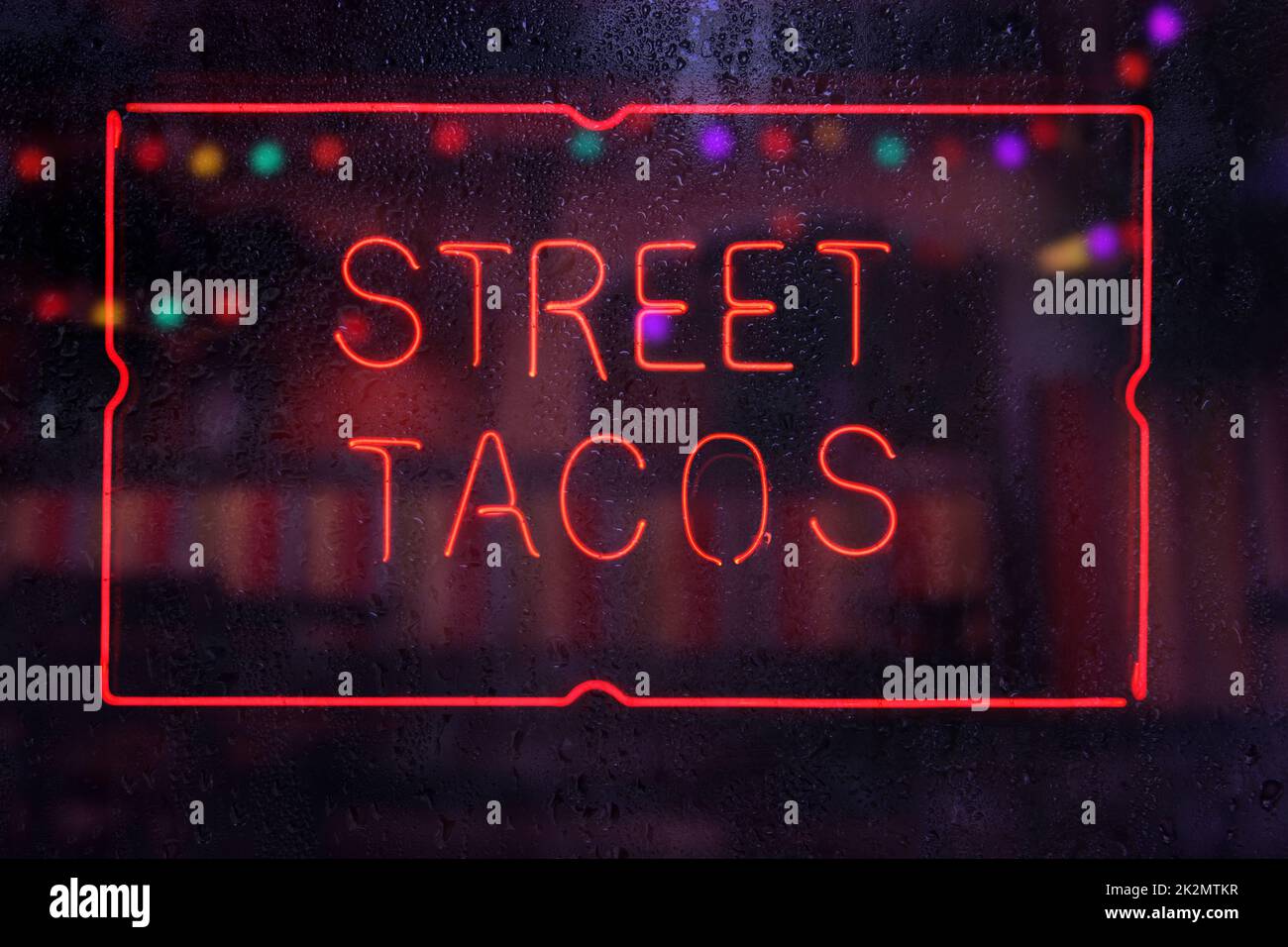 Neon Street Tacos Schild in Wet Rainy Window Stockfoto