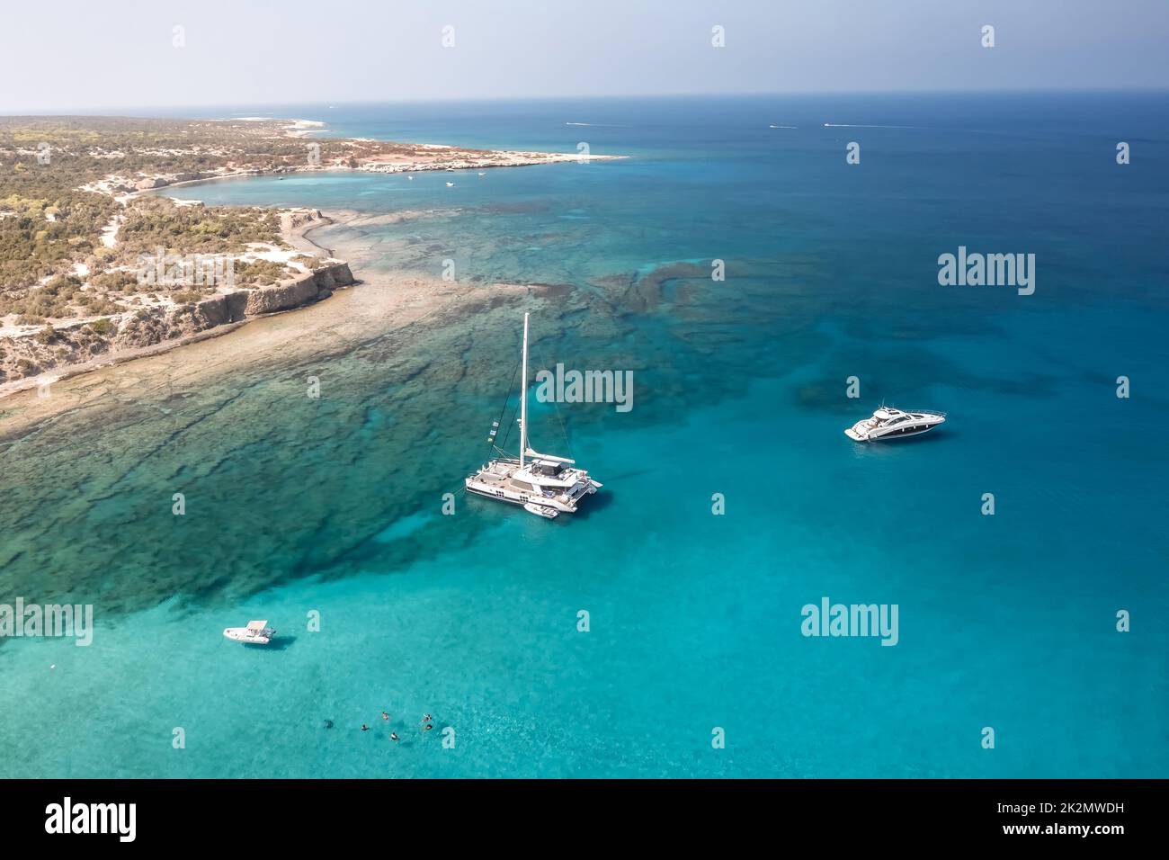 Luftaufnahme von drei Booten auf azurblauem klarem Wasser in der Nähe der felsigen Küste (Zypern) Stockfoto