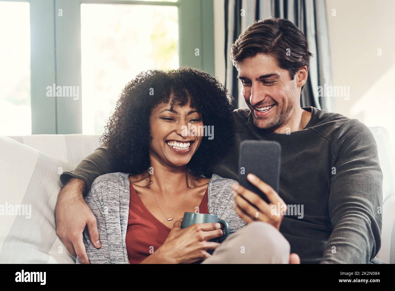 Sehen Sie sich an, was heute online an Trends liegt. Aufnahme eines liebevollen jungen Paares, das auf einer Couch sitzt und zu Hause eine gute Zeit miteinander verbringt. Stockfoto